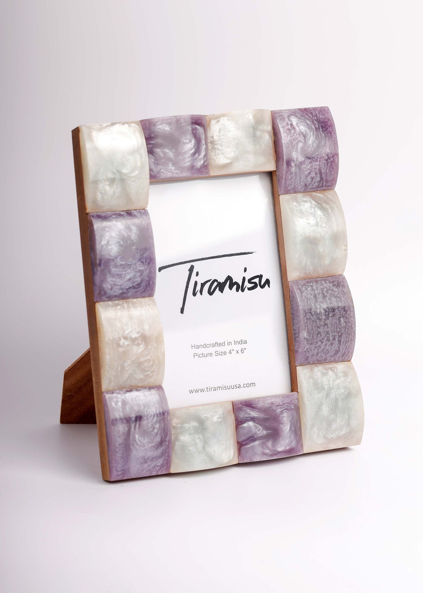 A picture frame with a rectangular wooden base and alternating marbled stone tiles in lavender purple, cream, and white, holding a white insert card with the brand name 'Tiramisa' printed on it.