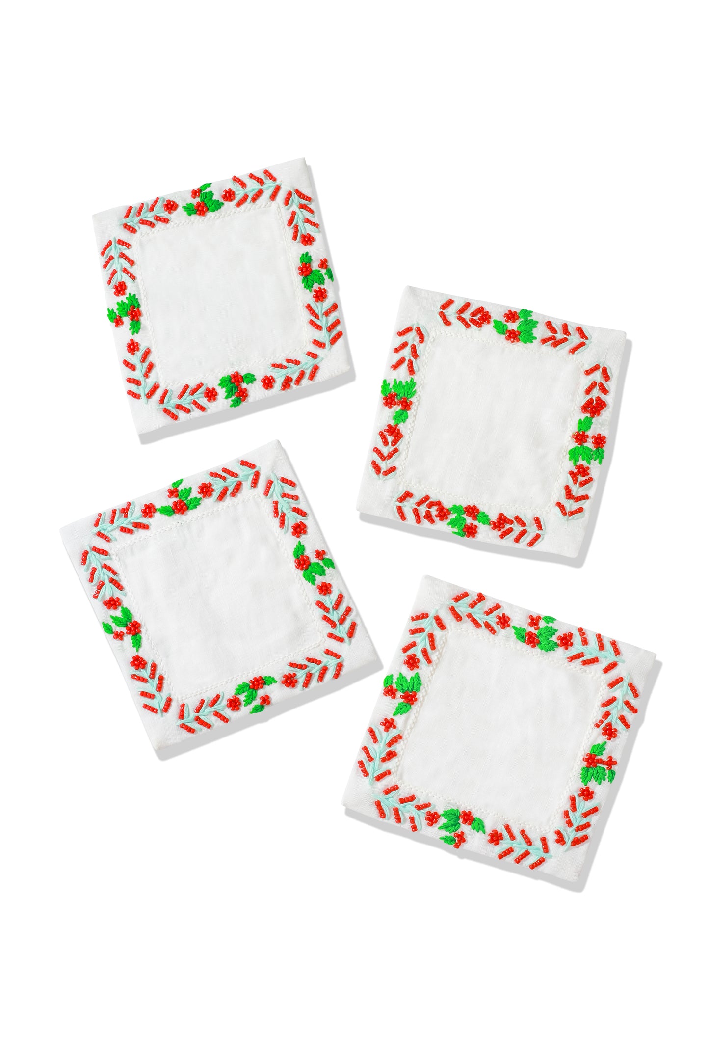 Set of four napkins with red and green border designs on a white background.