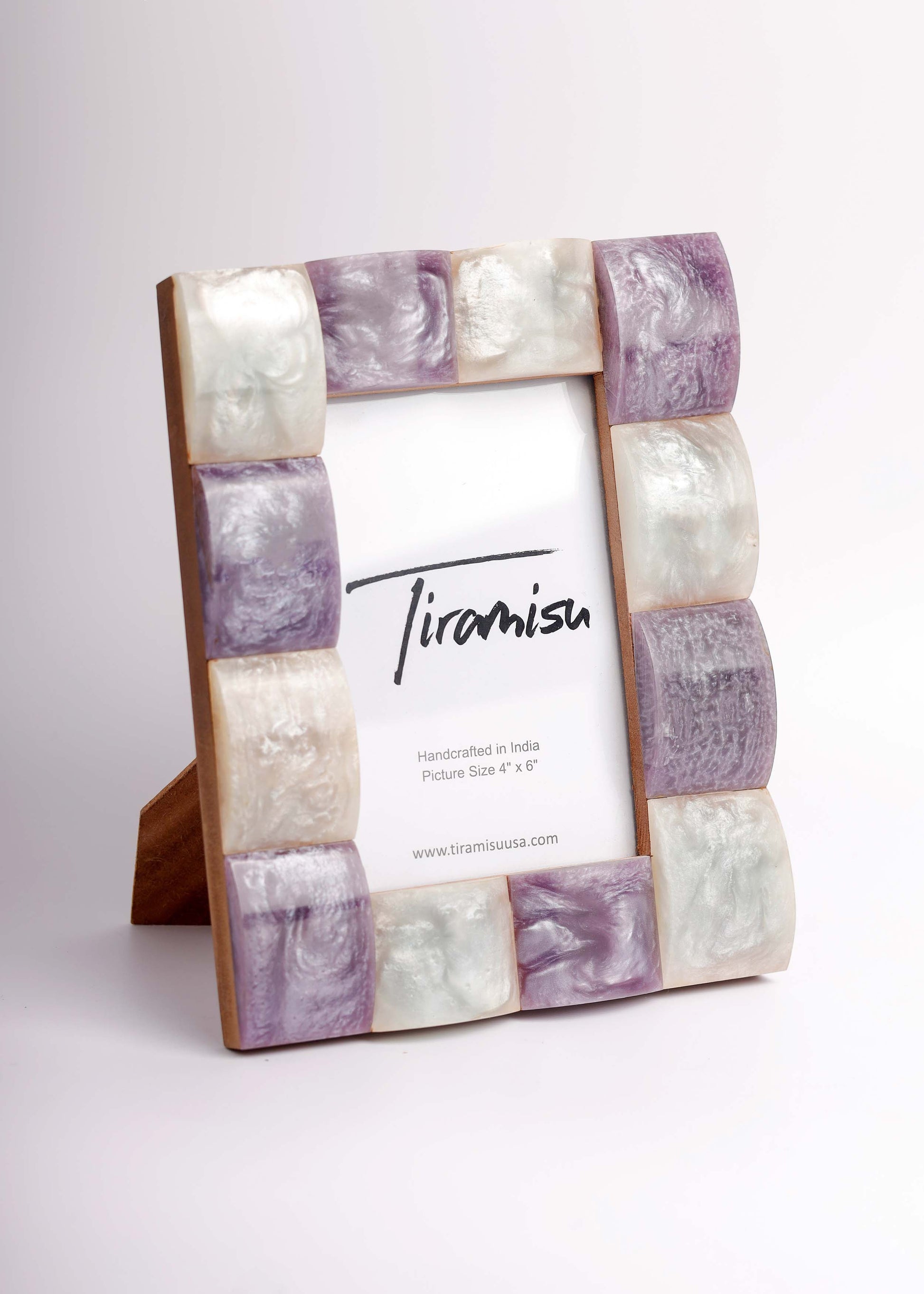 A picture frame with a rectangular wooden base and alternating marbled stone tiles in lavender purple, cream, and white, holding a white insert card with the brand name 'Tiramisa' printed on it.